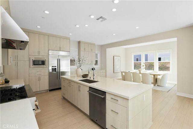 kitchen with under cabinet range hood, light wood-type flooring, built in appliances, and a sink