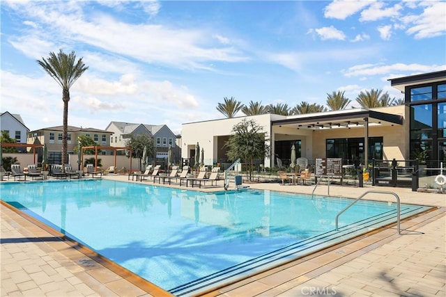 community pool with a residential view, fence, and a patio area