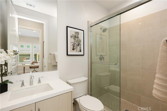 bathroom featuring vanity, a shower stall, toilet, and visible vents