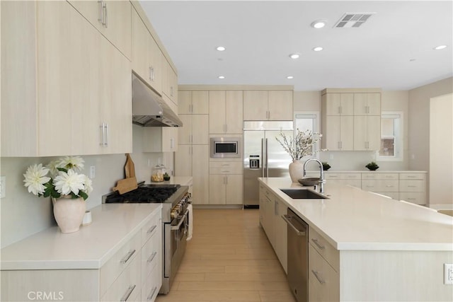 kitchen featuring visible vents, under cabinet range hood, a sink, light countertops, and built in appliances