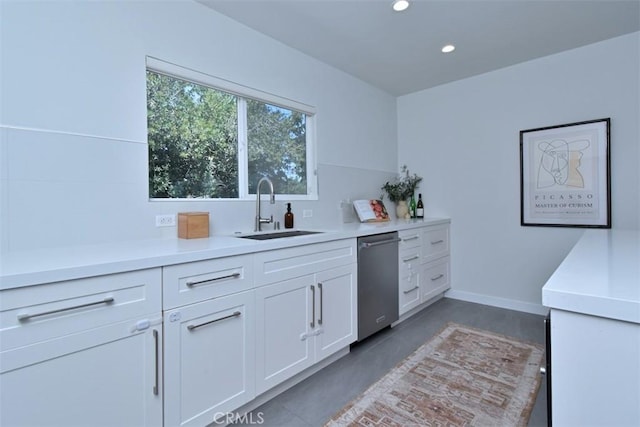 kitchen featuring dishwasher, light countertops, a sink, and white cabinets