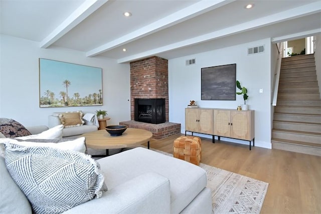 living room featuring visible vents, beamed ceiling, stairway, and wood finished floors