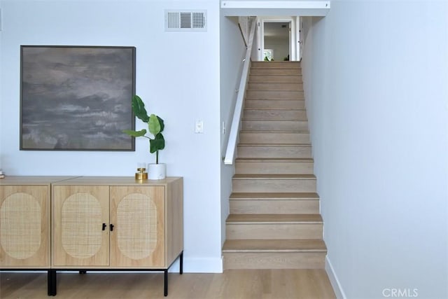 stairs featuring baseboards, visible vents, and wood finished floors