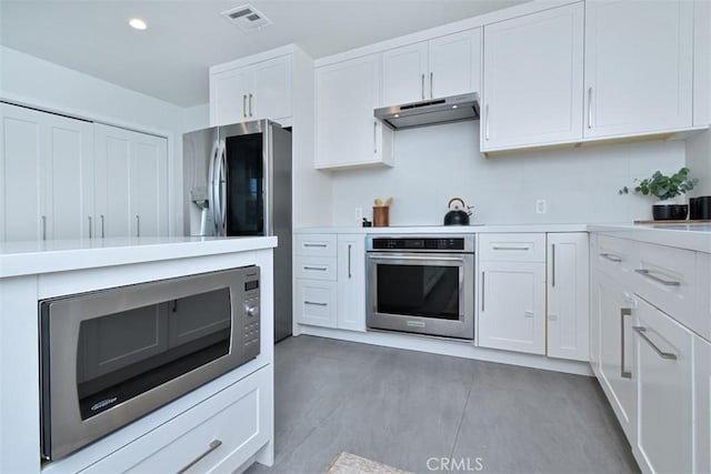 kitchen with under cabinet range hood, visible vents, white cabinets, light countertops, and appliances with stainless steel finishes