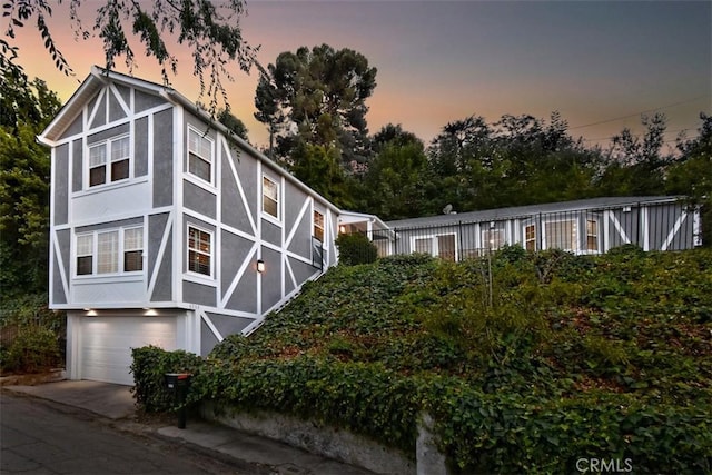 english style home featuring concrete driveway, an attached garage, and stucco siding