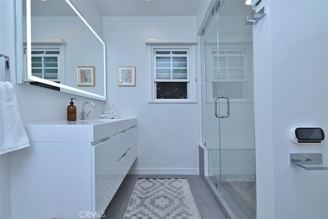 bathroom with baseboards, a shower stall, and vanity