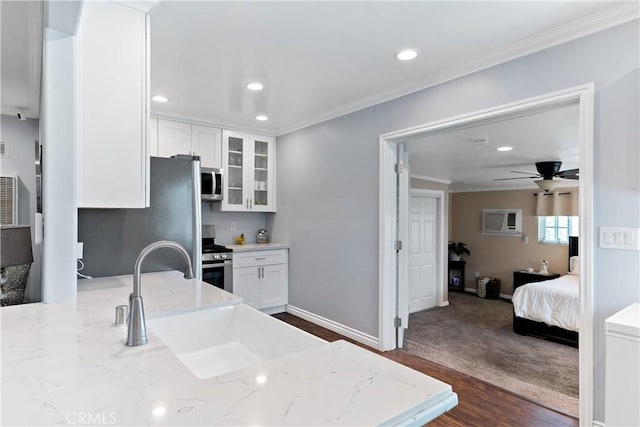 kitchen featuring recessed lighting, stainless steel appliances, white cabinetry, ornamental molding, and glass insert cabinets