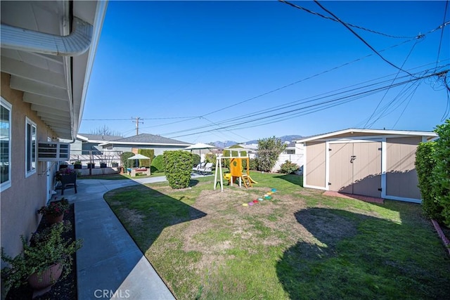 view of yard featuring an outbuilding, a storage shed, and a playground