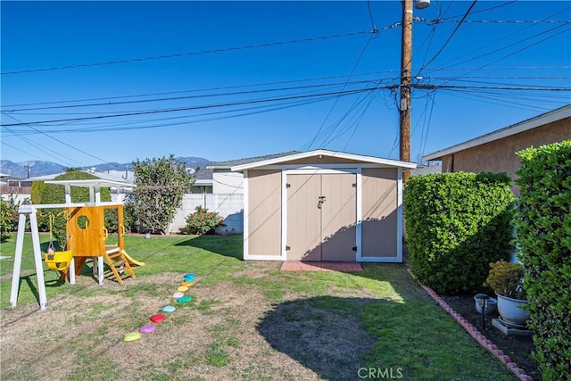 view of shed with a playground, a mountain view, and fence