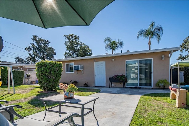 exterior space featuring a lawn, a patio area, a wall mounted air conditioner, and stucco siding