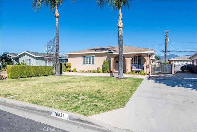 view of front of property with a front yard, a gate, fence, and stucco siding