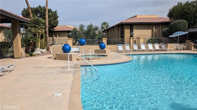 community pool featuring a community hot tub, a patio, and fence