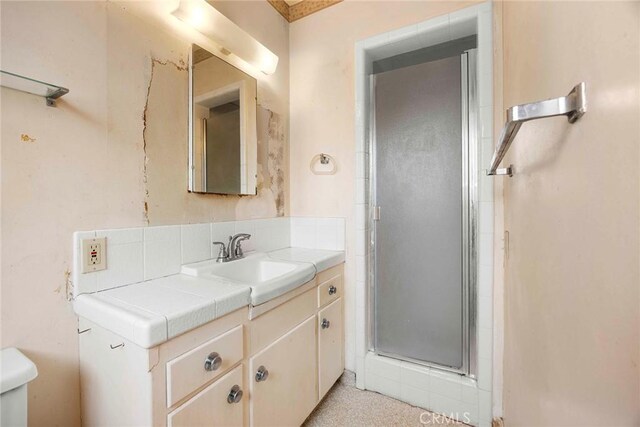 bathroom with toilet, a stall shower, and vanity