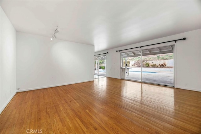 empty room with baseboards and wood finished floors