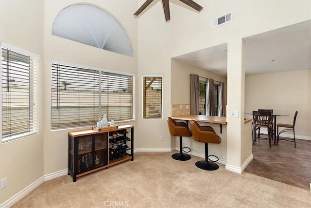 interior space featuring carpet floors, a high ceiling, visible vents, and baseboards