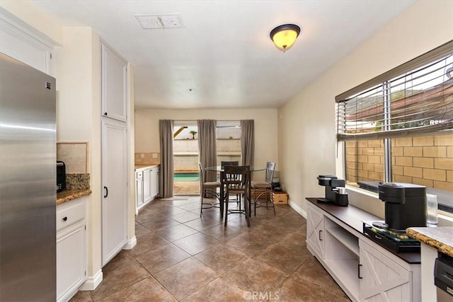 interior space with white cabinetry, stainless steel refrigerator, and a wealth of natural light