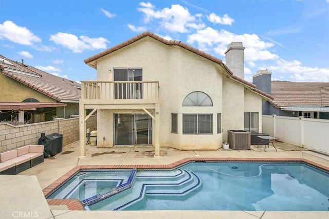 rear view of house featuring a patio, a chimney, stucco siding, a balcony, and a fenced backyard