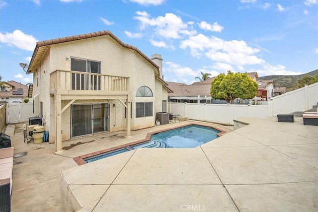 rear view of house featuring a fenced in pool, a patio, stucco siding, a balcony, and a fenced backyard