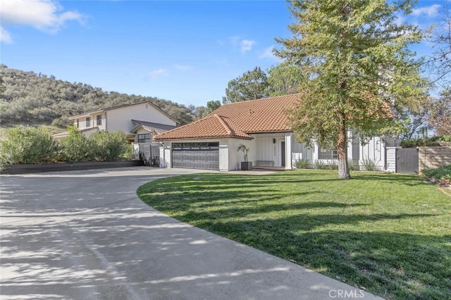 mediterranean / spanish-style home featuring a garage, a tile roof, concrete driveway, stucco siding, and a front lawn