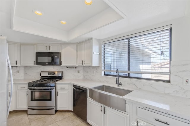 kitchen featuring light tile patterned floors, a sink, white cabinets, black appliances, and tasteful backsplash