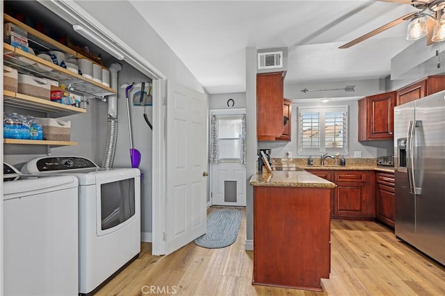 kitchen with light wood-style flooring, washing machine and dryer, stainless steel fridge, and visible vents