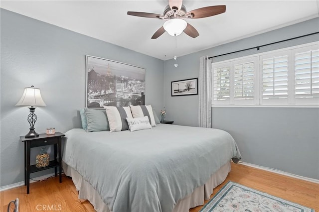 bedroom with a ceiling fan, baseboards, and wood finished floors