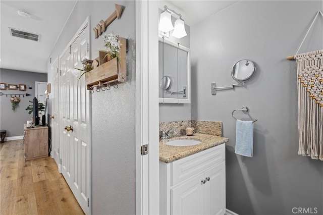 bathroom with baseboards, visible vents, wood finished floors, and vanity