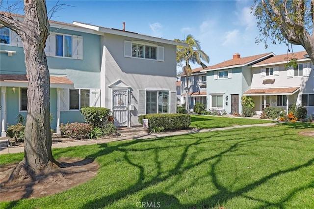 rear view of property featuring a yard and stucco siding