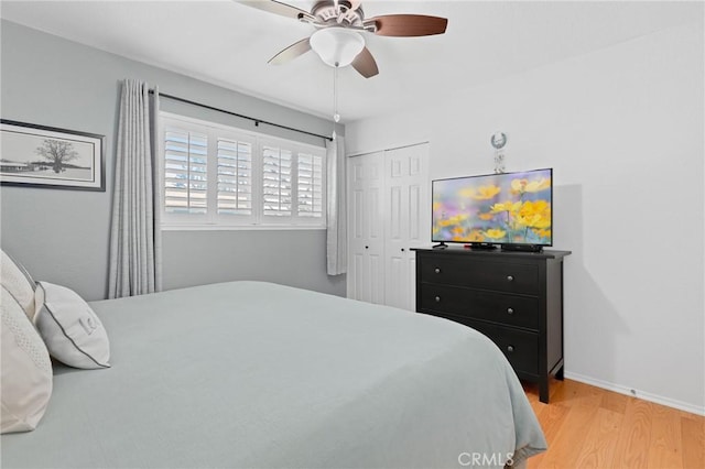 bedroom featuring light wood-type flooring, a closet, ceiling fan, and baseboards