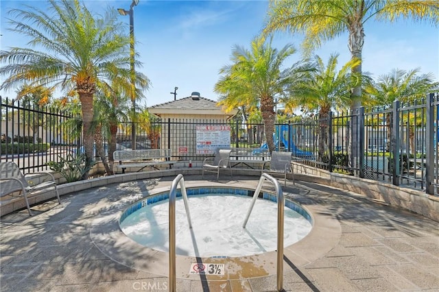 view of pool with fence and a hot tub