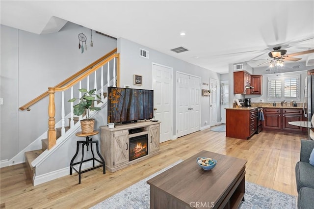 living area with light wood-type flooring, ceiling fan, and visible vents