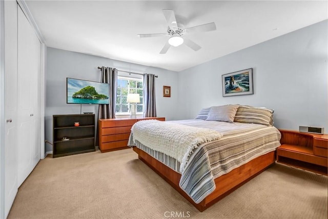 bedroom with light carpet, ceiling fan, and a closet