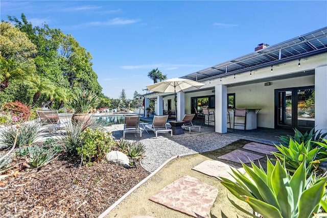 view of patio / terrace featuring outdoor dry bar, french doors, and an outdoor pool