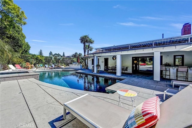 outdoor pool with outdoor dry bar and a patio area