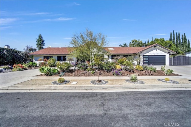 ranch-style home featuring an attached garage, a gate, fence, and concrete driveway