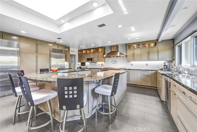 kitchen with a spacious island, visible vents, appliances with stainless steel finishes, wall chimney exhaust hood, and tasteful backsplash