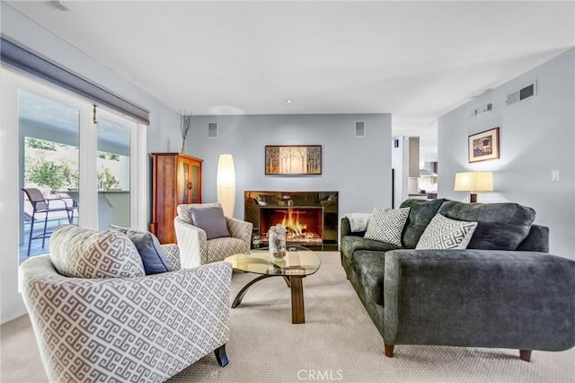 living area with a warm lit fireplace and visible vents