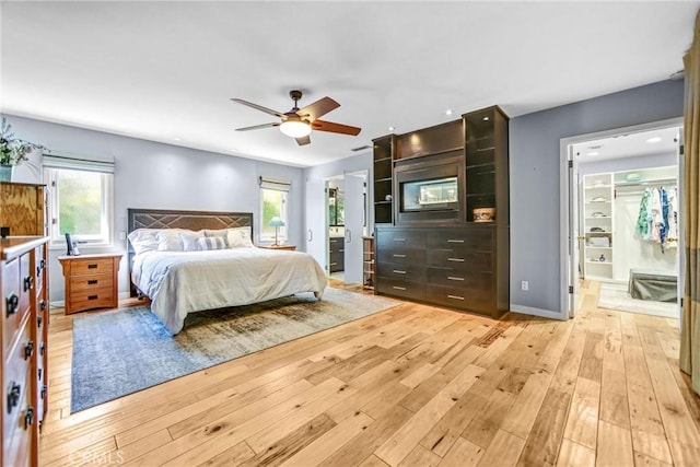 unfurnished bedroom with light wood finished floors, multiple windows, baseboards, and connected bathroom