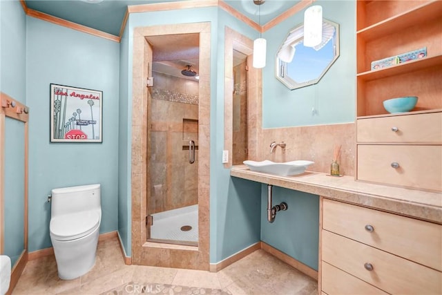 full bathroom with a stall shower, baseboards, toilet, crown molding, and vanity