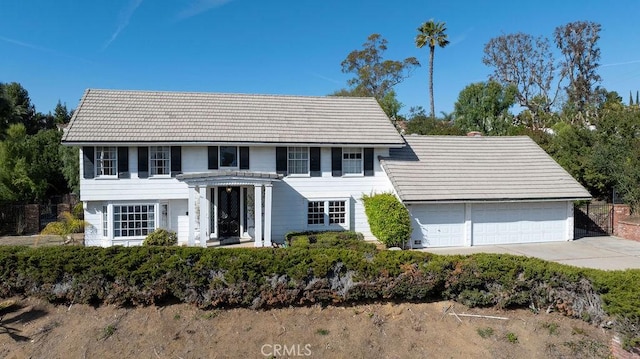 colonial-style house with an attached garage, driveway, and a tile roof