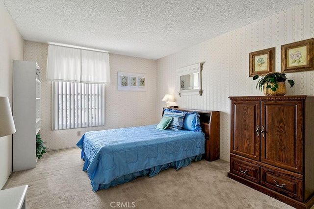 bedroom featuring light colored carpet, a textured ceiling, and wallpapered walls