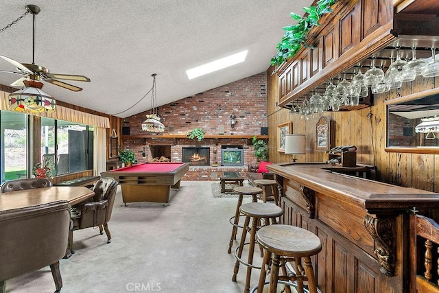 rec room featuring carpet floors, vaulted ceiling, wood walls, a bar, and a textured ceiling