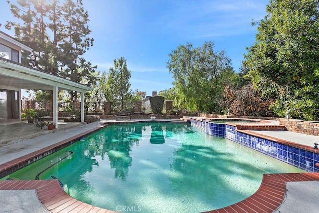 view of swimming pool with a pool with connected hot tub, fence, and a patio