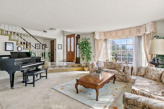 carpeted living room with a textured ceiling, stairway, and visible vents