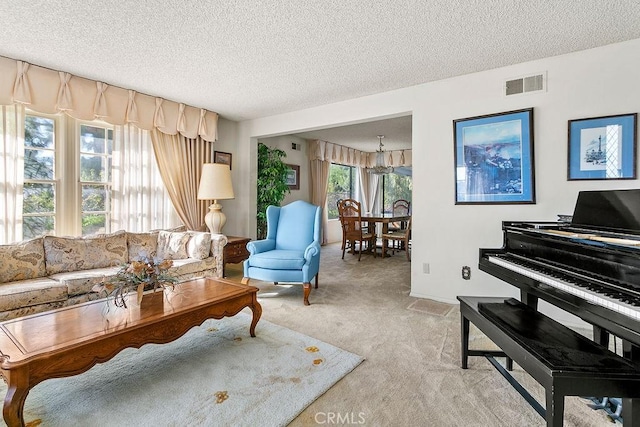 living area featuring visible vents, light carpet, and a textured ceiling