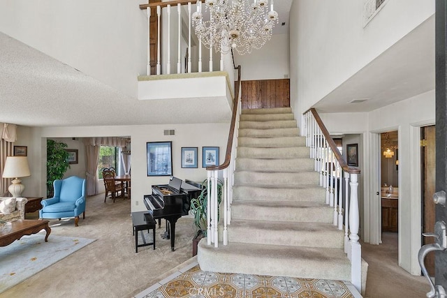 staircase with visible vents, a textured ceiling, carpet, and a towering ceiling