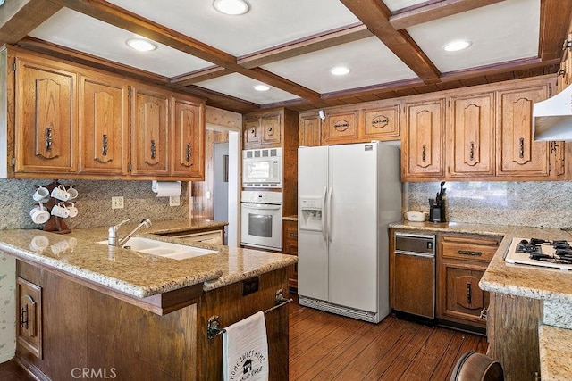 kitchen featuring a peninsula, white appliances, dark wood-style flooring, coffered ceiling, and a sink