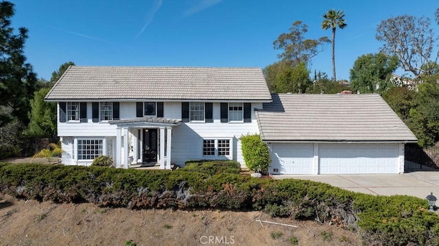 colonial house with a garage, concrete driveway, and a tile roof