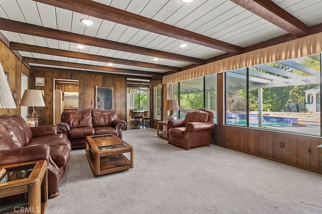 carpeted living area with wooden walls, beam ceiling, and recessed lighting