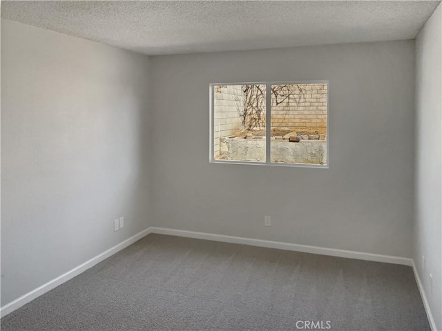 spare room featuring a textured ceiling, carpet floors, and baseboards